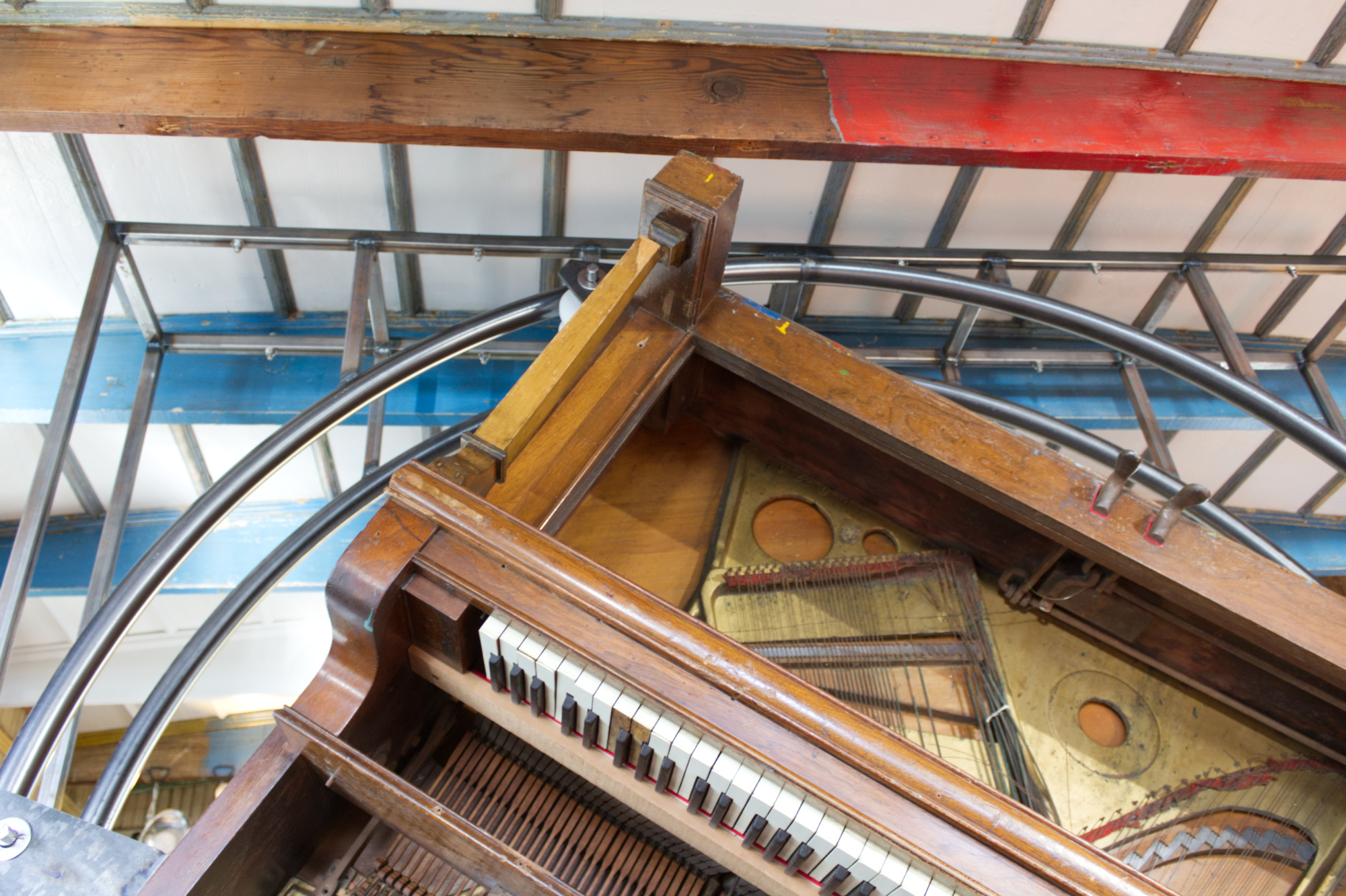 Detail of piano upside down inside its framework, against the ceiling of The Blue Cabin